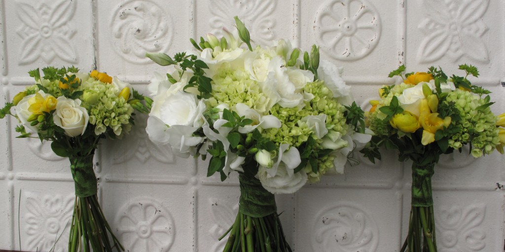 photo of 3 wedding bouquets lined up against a white tin background