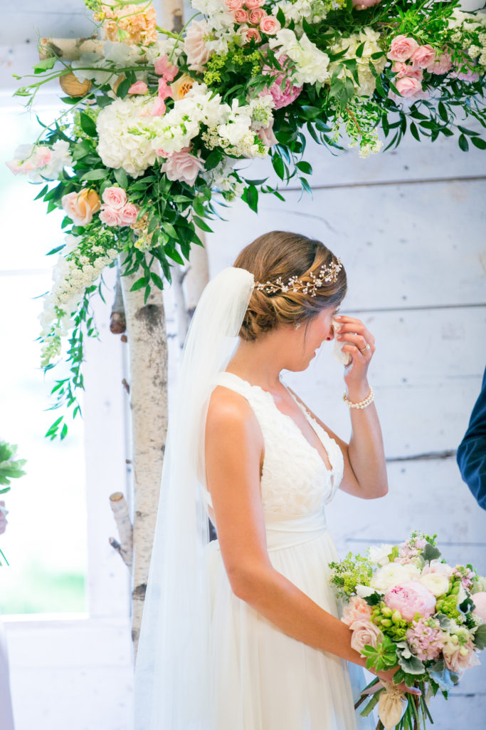 bride beneath wedding arbor