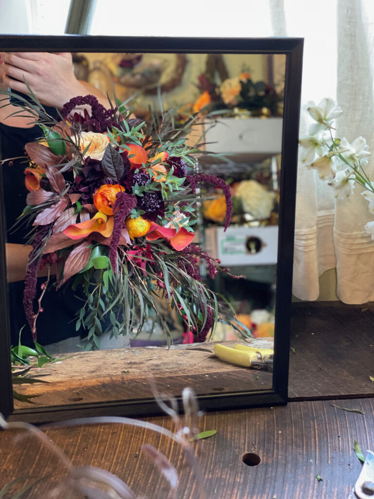 florist holding bouquet up in mirror